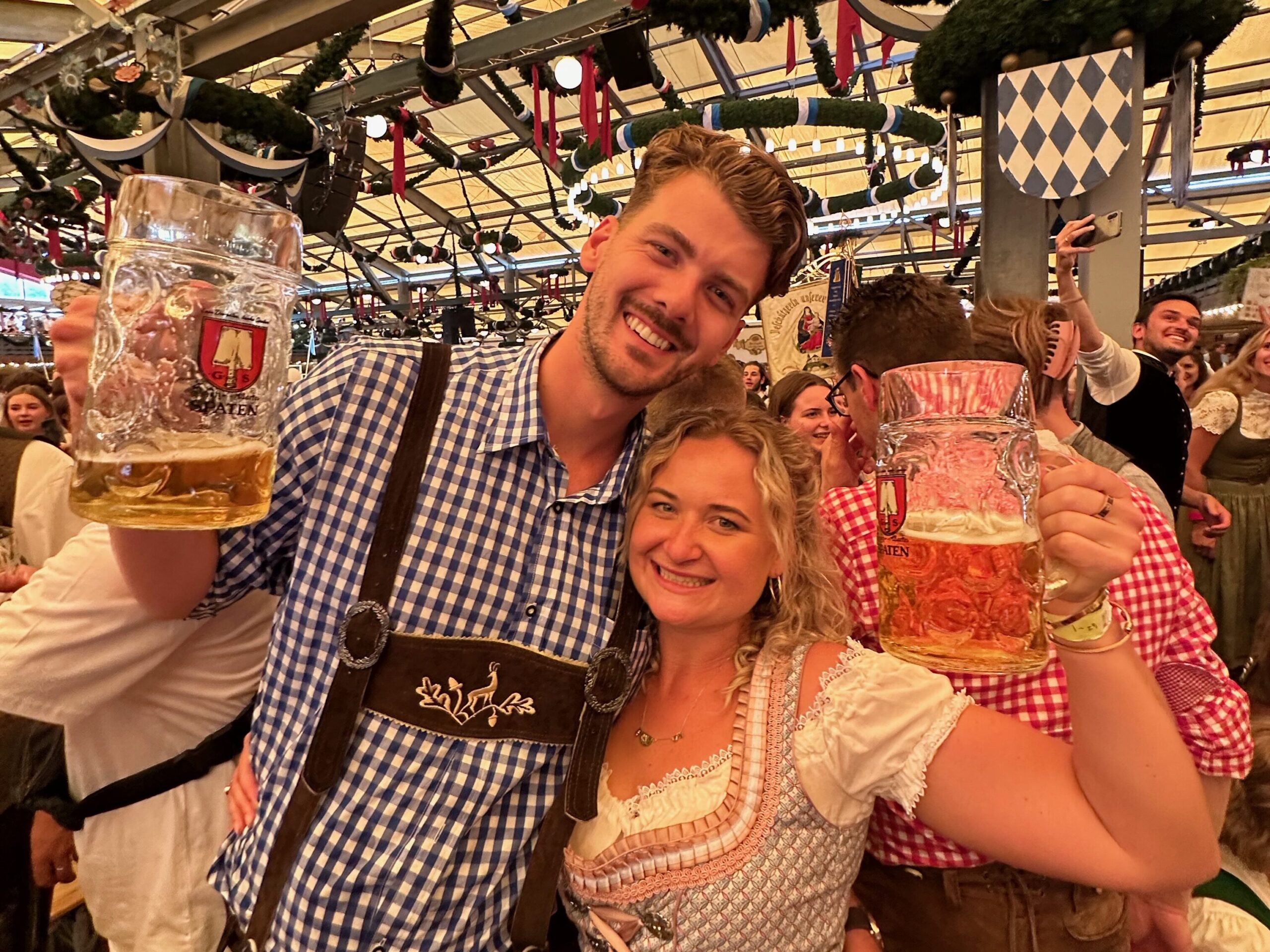 “Harry and Renee dressed in traditional Bavarian attire, enjoying beer and pretzels at Oktoberfest in Munich, Germany”